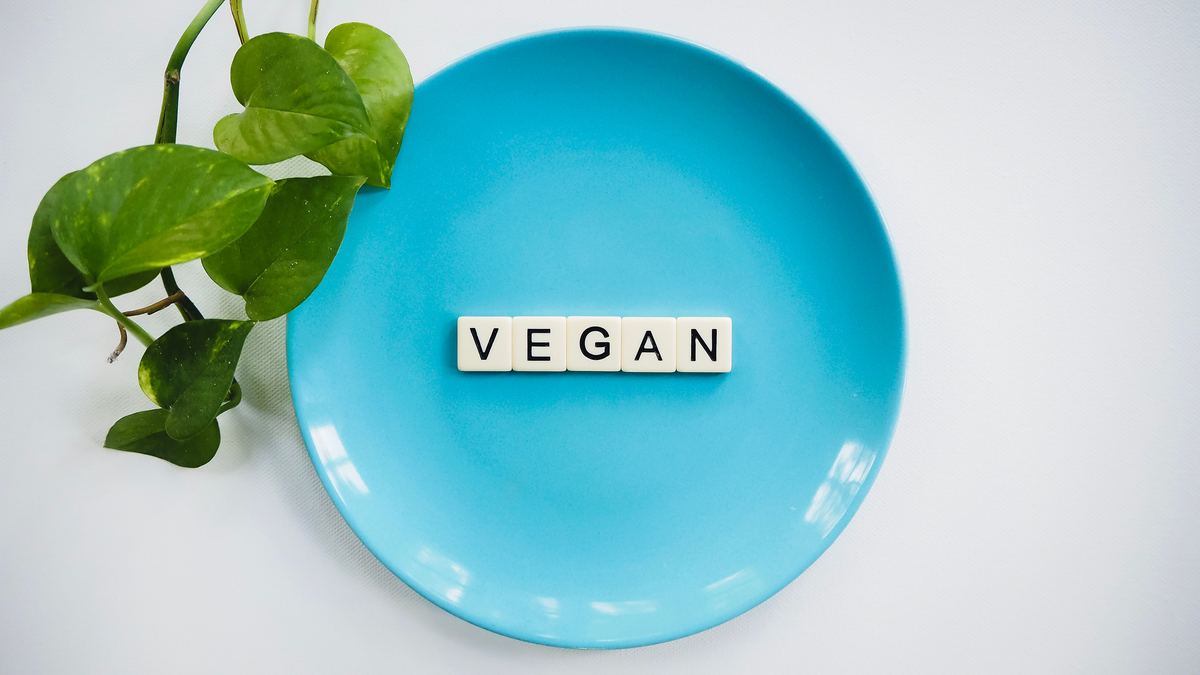 Illustrative stock photograph of a plant beside letter tiles spelling vegan