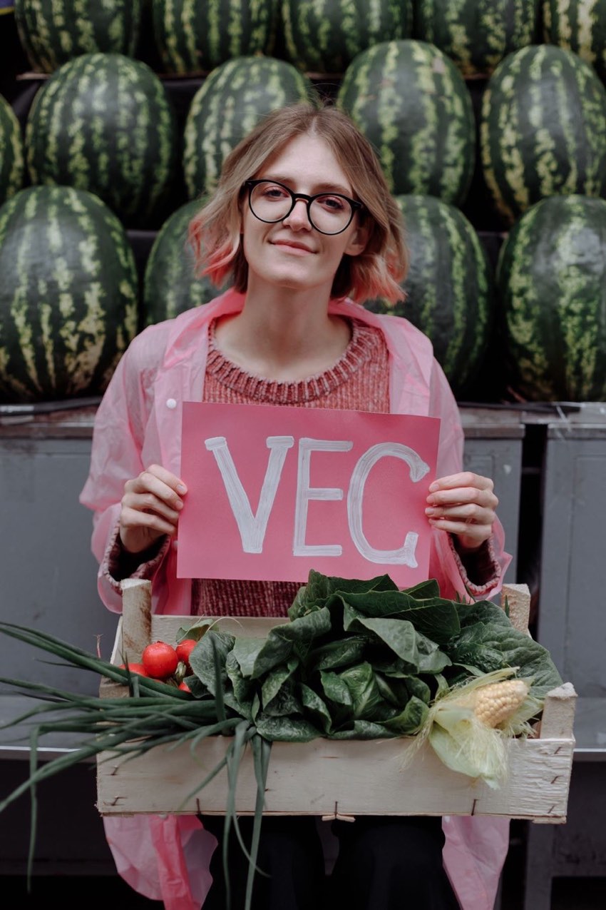 Illustrative stock photograph of an adult holding a vegetable sign at a market